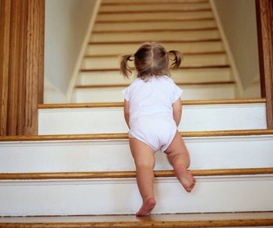 Малыш в возрасте 15 месяцев поднимается по лестнице